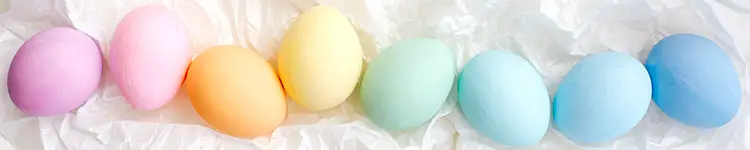 a row of easter eggs in purple, pink, orange, yellow, green, seafoam, sky blue and primary blue colors