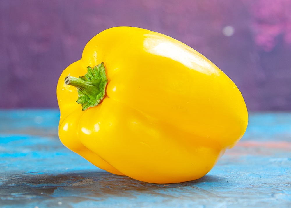 yellow big bell pepper on blue tabletop