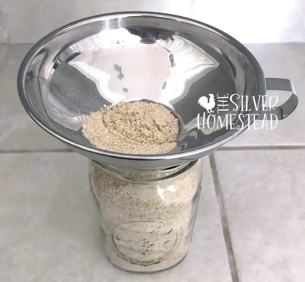 powdered game bird feed in a funnel and mason jar to illustrate How to Make Powdered Game Bird Feed for Coturnix and Button Quail Chicks